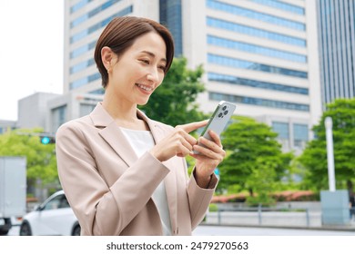 Asian businesswoman using the smartphone outdoor - Powered by Shutterstock