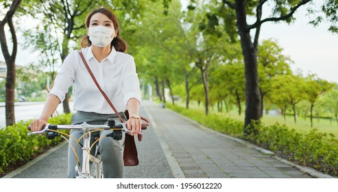 Asian businesswoman wear face mask and commute by bicycle through the city