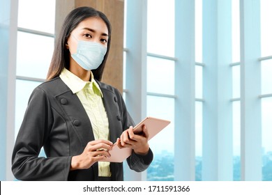 Asian businesswoman wearing a flu mask standing while using a tablet  in the hospital - Powered by Shutterstock