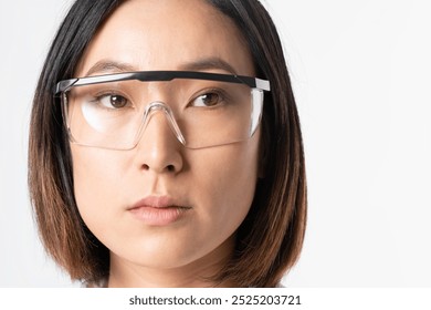 Asian businesswoman wearing safety glasses. Close-up of an Asian businesswoman with safety glasses. Safety glasses on an Asian businesswoman. Protective eyewear on an Asian businesswoman. - Powered by Shutterstock