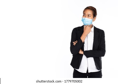 Asian Businesswoman Wearing Surgical Face Mask In Black Suit Jacket, Poses Like Thinking, Studio Lighting Isolated On White Background, Coronavirus, COVID-19 Concept 
