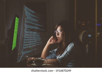 Asian Businesswoman working hard with front of computer desktop with programming source code and motion graphic over computer screen in work place at late times with exciting and serious action - Powered by Shutterstock