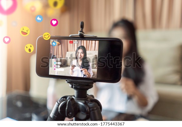 Asian businesswoman working from home live video\
interaction with customers using camera device vlogging selling\
make up products, viral internet social media influencer\
interacting to live\
audience