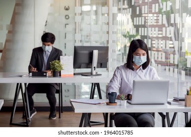 Asian businesswoman working on a laptop at the office wearing a mask to prevent germs blurred back. - Powered by Shutterstock