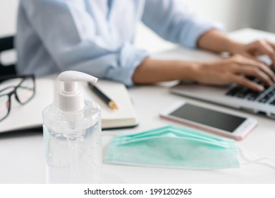 Asian businesswoman working at workplace with face mask and hand sanitizer on table during the coronavirus crisis. Working from home, business and health care concept. - Powered by Shutterstock