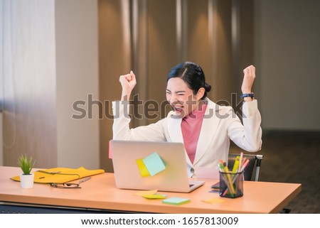 Asian businesswomen hapiness celebrating when checking success goal via technology laptop in modern office or coworking space, Working for pleasure and success