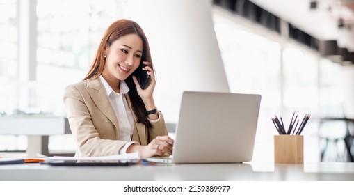 Asian businesswomen have the joy of talking on the phone with a laptop computer tablet on the office desk. doing accountant on a calculator to calculate business data documents. - Powered by Shutterstock