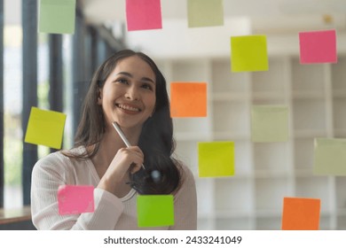 Asian businesswomen use post-it notes on glass walls to write strategic business plans for development to grow to success.	 - Powered by Shutterstock