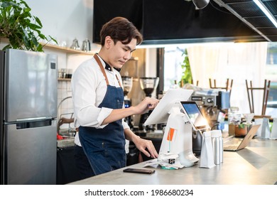 Asian Cafe Business Male Owner Checking Takeaway Order From Touch Screen On Counter Bar. Restaurant Barista Worker Prepare Food For Pick Up Delivery Takeout For Customer. Food Shopping Online Concept.