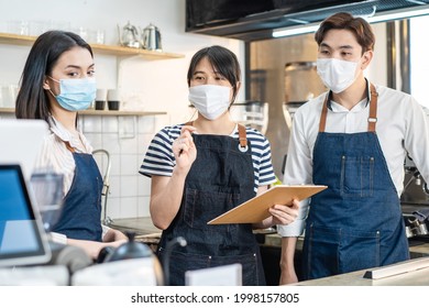 Asian Cafe Manager Leader Explain Job Working To Barista And Waitress. Beautiful Coffeehouse Worker Wear Mask Due To Covid19 Pandemic Meeting And Discuss Work Plan In Store Before Restaurant Reopen.