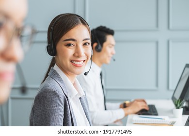 Asian call center team, customer service, telesales in formal suit wearing headset or headphone talking with customer in modern office - Powered by Shutterstock