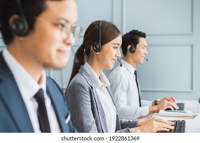 Asian Call Center Team, Customer Service, Telesales In Formal Suit Wearing Headset Or Headphone Talking With Customer In Modern Office