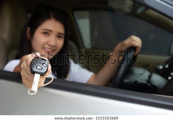 Asian car\
driver woman smiling showing car\
key.\
