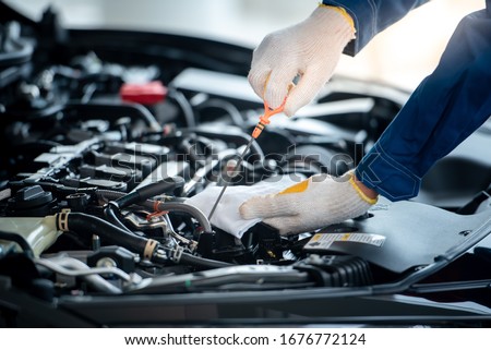 Asian car mechanic in an auto repair shop is checking the engine. For customers who use cars for repair services, the mechanic will work in the garage.
