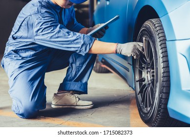 Asian Car Mechanic Technician Holding Clipboard And Checking To Maintenance Vehicle By Customer Claim Order In Auto Repair Shop Garage. Wheel Tire Repair Service. People Occupation And Business Job