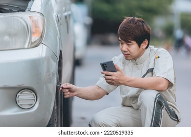 Asian Car Mechanic Technician Sitting And Checking Car Tyres Or Car Wheel In In Auto Repair Shop Garage. Wheel Tire Repair Service.