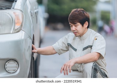 Asian Car Mechanic Technician Sitting And Checking Car Tyres Or Car Wheel In In Auto Repair Shop Garage. Wheel Tire Repair Service.