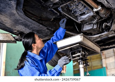 Asian car mechanic woman fixing gear shaft underneath vehicle in auto repair garage - Powered by Shutterstock