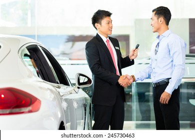 Asian Car Salesman Selling Auto To Customer