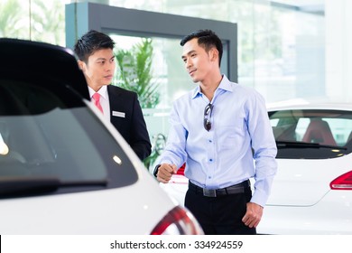 Asian Car Salesman Selling Auto To Customer