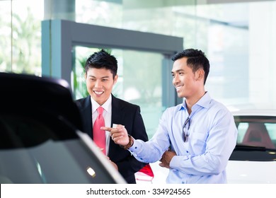 Asian Car Salesman Selling Auto To Customer