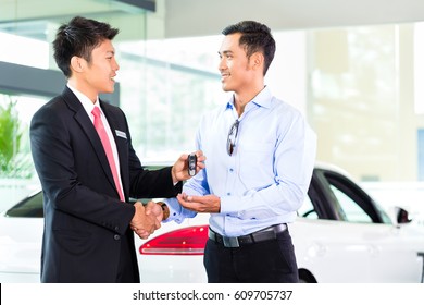 Asian Car Salesman Selling Auto To Customer