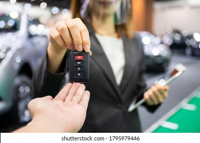 Asian Car Seller Wearing Face Mask Presents Car And Passing New Car Key To Customer After Purchased While Coronavirus Pandemic