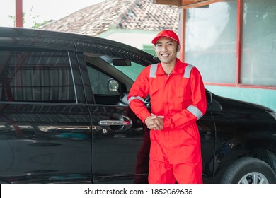 Asian Car Washer Wearing Red Uniform Smiling Leaning On The Car After Finishing Car Wash At Work