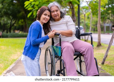 Asian Careful Caregiver Or Nurse Taking Care Of The Patient In A Wheelchair.  Concept Of Happy Retirement With Care From A Caregiver And Savings And Senior Health Insurance, A Happy Family