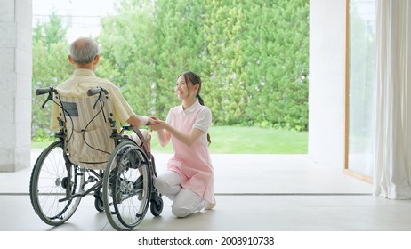 Asian Caregiver Assisting Elderly Man