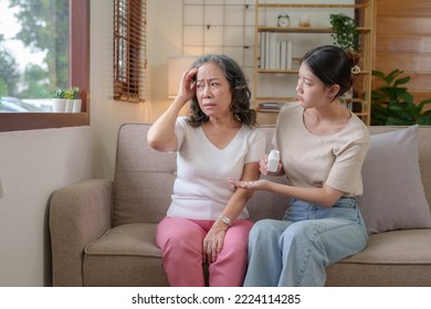 Asian Caregiver Or Daughter Take Care Of The Elderly At Home In The Living Room, Providing Timely Medication.