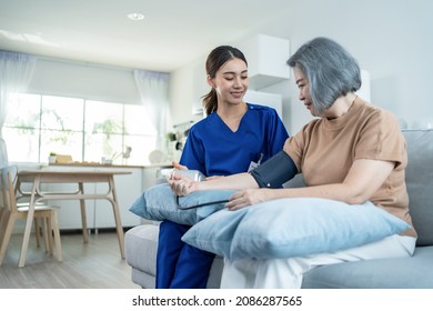 Asian caregiver doctor examine older patient use blood pressure gauge. Young woman therapist nurse at nursing home taking care of senior elderly woman sit on sofa. Medical insurance service concept