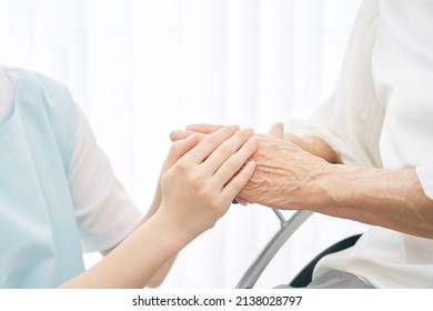 Asian caregiver holding Asian senior woman's hands, no face - Shutterstock ID 2138028797