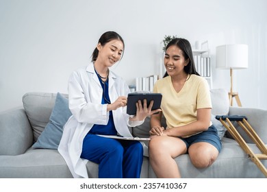 Asian caregiver psychology doctor examine and listen to female amputee. Beautiful woman nurse give advise and consult to help young patient in living room at home. Psychologic health care lifestyles. - Powered by Shutterstock