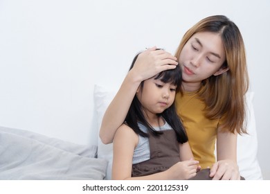 Asian Caring Mother holding her sick daughter and measuring temperature with her hand.  - Powered by Shutterstock