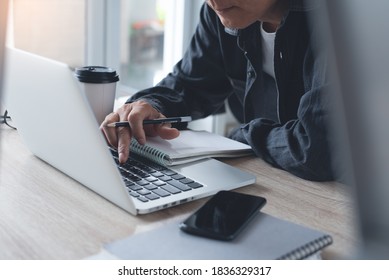 Asian Casual Business Man Working On Laptop Computer, Browsing Internet And Taking Notes On Paper Notebook At Home Office. Student Concentrate Learning Online And Lecturing On Notepad, Close Up