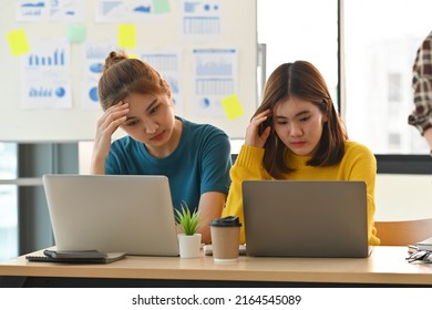 Asian Casual Tried Office Workers Sitting On Using Computer Laptop To Solve Problems Together With Teammate In The Modern Office Decoration. Business Stressed Situation. Business And Financial Concept