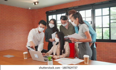 Asian And Caucasian Business Man And Woman Wear Face Mask Meeting In Front Op Laptop Computer. Concept Of New Normal Work After Covid 19 Pandemic