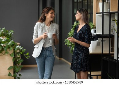 Asian and Caucasian ethnicity women colleagues met in office hall chatting enjoy friendly warm conversation, multi-ethnic mates having informal talk drink tea or coffee take break distracted from work - Shutterstock ID 1530452789