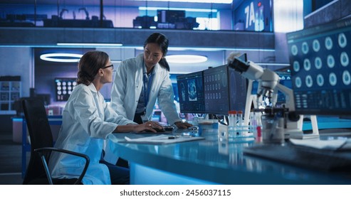 Asian And Caucasian Female Doctors Talking In Medical Research Center And Using Desktop Computer To Analyze Brain CT Scans. Surgeon And Neuroscientist Discussing Solutions For Treating Cancer Patients - Powered by Shutterstock