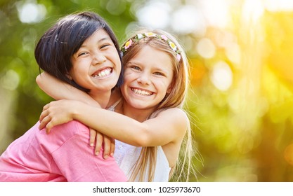 Asian and Caucasian girl hug each other laughing in the summer in the nature - Shutterstock ID 1025973670