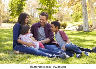 Asian Caucasian Mixed Race Family Sitting On Grass In A Park