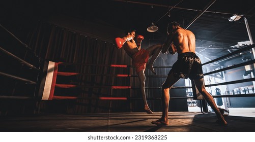 Asian and Caucasian Muay Thai boxer unleash knee attack in fierce boxing training session, delivering knee strike to sparring trainer, showcasing Muay Thai boxing technique and skill. Spur