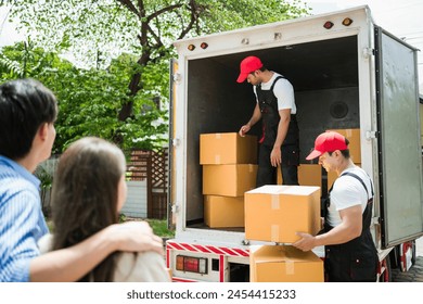 Asian and Caucasian workers in uniform unloading cardboard boxes from the truck. Delivery men unloading boxes and check the checklist with their coworkers. Professional delivery and moving service. - Powered by Shutterstock