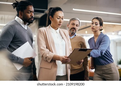 Asian CEO and her team analyzing report data during a briefing at corporate office. - Shutterstock ID 2109198200