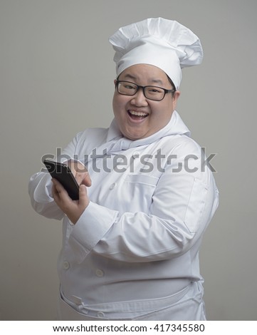 Asian chef with mobile device in her hand on plain background