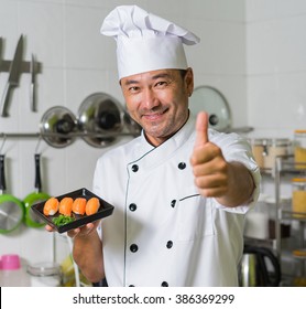 Asian chef sgowing plate with sushi and OK. Focus on sushi.  - Powered by Shutterstock