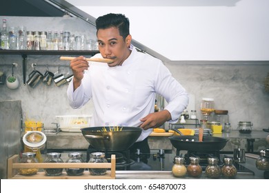 Asian chef is tasting food by using wooden ladle at the kitchen of a restaurant - Powered by Shutterstock