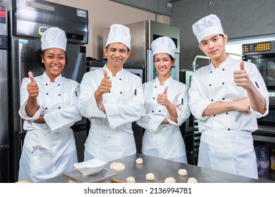 Cocinero asiático con traje y sombrero de chef, cocinando juntos en la cocina. Equipo de cocineros profesionales en uniforme que preparan las comidas para un restaurante en la cocina.