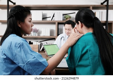 Asian Chief Physician Man Is Meeting With Surgeon Doctor Women Wear Blue And Green Surgical Gown Is Serious. Medical Team Are Talking And Researching With Laptop For Treatment Of Patients At Hospital.